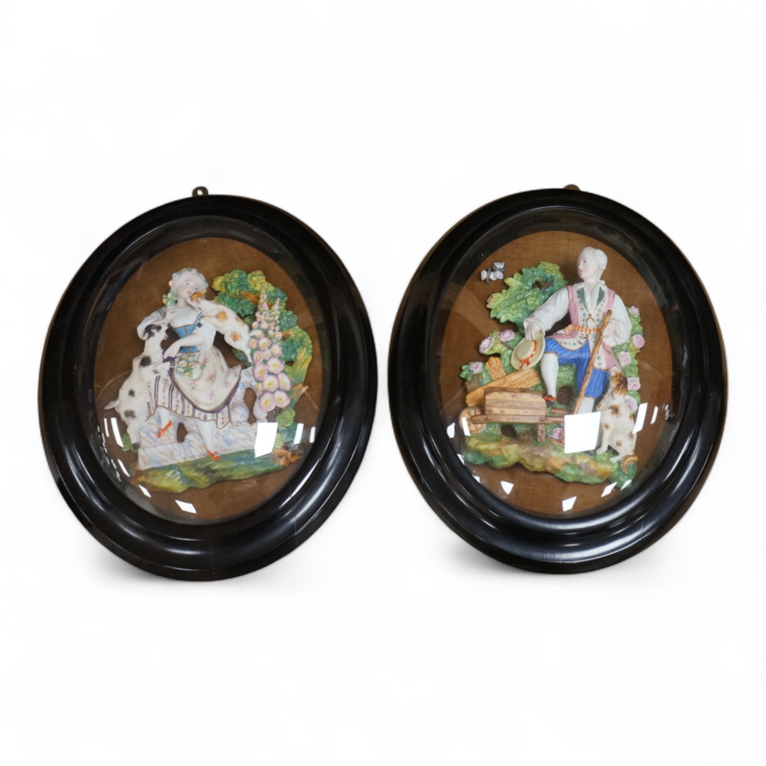 A pair of oval glazed biscuit porcelain plaques depicting figures, housed in ebonised frames, latter 43x34cm